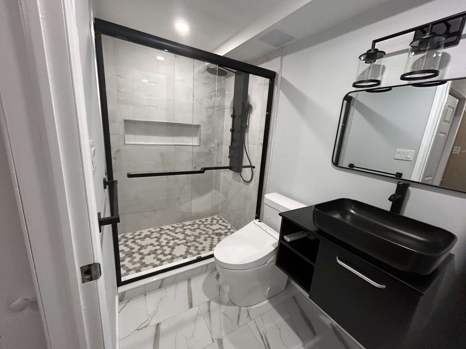 White kitchen with black appliances and wood flooring